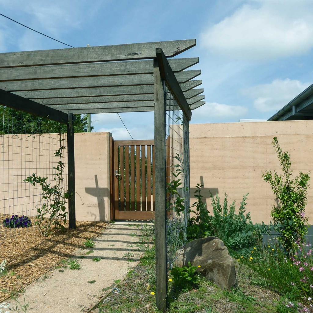 Rammed earth courtyard with gate and pergola